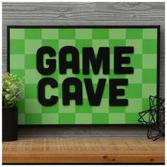 a green sign that says game cave next to a potted plant on a shelf