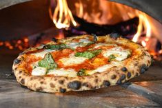 a pizza sitting in front of an open fire