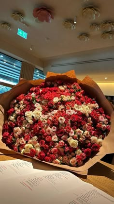 a large bouquet of red and white flowers in a paper wrapper on top of a table