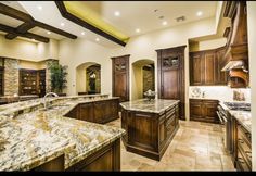 a large kitchen with marble counter tops and wooden cabinets