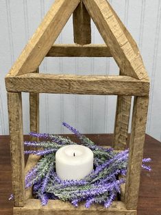 a small wooden frame with a candle and lavenders in it sitting on a table