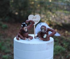 two monkey figurines sitting on top of a white cake