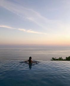 a woman swimming in the ocean at sunset