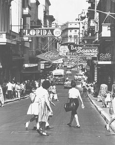 an old black and white photo of people walking down the street