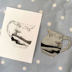 a piece of paper next to a teapot on a polka dot tablecloth with a card