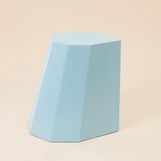 a light blue vase sitting on top of a white table next to a beige wall