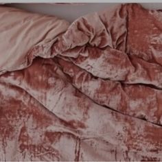 an unmade bed with a pink comforter on top of it and a white pillow