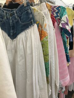 clothes are hanging on racks in a clothing store, with one woman's jeans and the other women's blouses