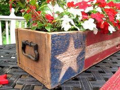 a wooden box with flowers in it on top of a table next to a potted planter