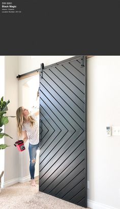 a woman standing in front of a black door with an arrow design on the side