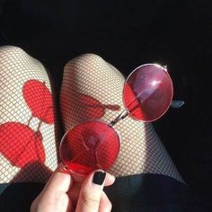 a pair of red glasses with hearts on them are being held up by someone's hand