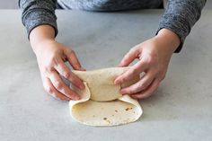 a person is making tortilla dough on a table with one hand reaching for it