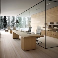 an office with glass walls and wooden flooring in the center, along with two desks that have computers on them