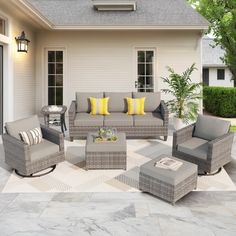 an outdoor patio with grey wicker furniture and yellow pillows