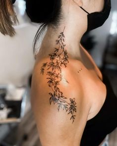 the back of a woman's neck with small flowers on her left shoulder and right arm