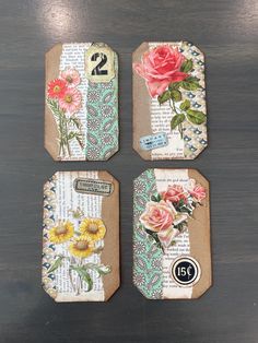 four tags with flowers on them sitting on top of a wooden table next to each other