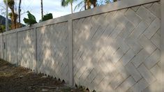 a white brick fence with trees in the background