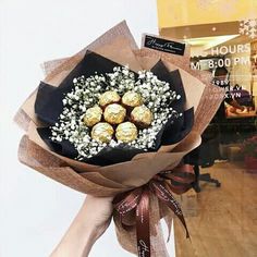 a hand holding a bouquet of flowers and chocolates