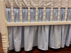 a white crib with blue bedding and wooden floors