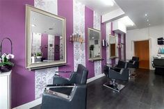 a hair salon with purple and white striped walls, chairs and mirrors on the wall