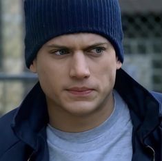 a young man wearing a beanie looking at the camera with an intense look on his face