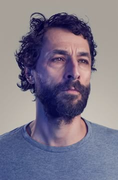 a man with curly hair and beard wearing a blue shirt