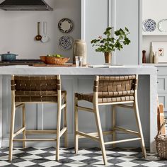 two chairs sitting at a kitchen table with an island in the middle and plates hanging on the wall