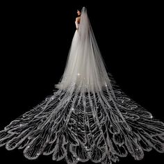 a woman in a wedding dress standing on top of a large white feathered veil