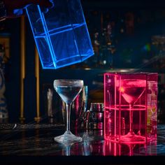 a person is pouring some liquid into a glass in front of several cubes and bottles