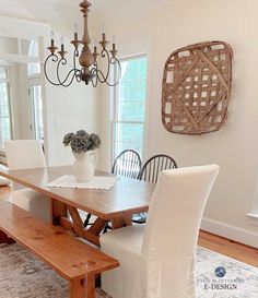 a dining room table with two chairs and a bench in front of the chandelier