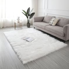 a living room with a couch, chair and rug on the floor in front of a window