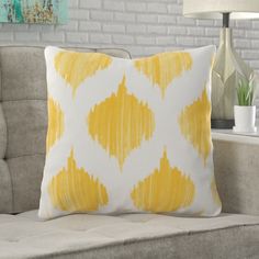 a yellow and white pillow sitting on top of a couch