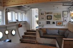 a living room filled with lots of furniture and pictures on the wall next to stairs