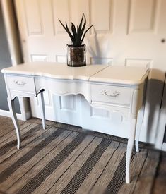 a white desk with two drawers and a potted plant sitting on top of it