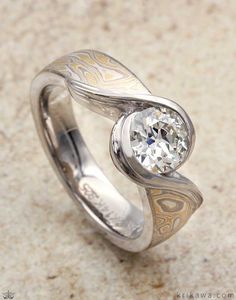 an artisticly designed wedding ring with a diamond in the center, on a marble surface