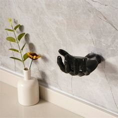 there is a vase with a flower in it and a black cat hook on the wall