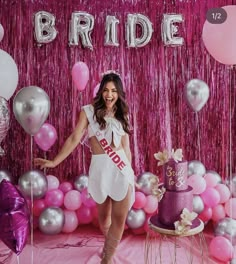 a woman standing in front of a cake and balloons