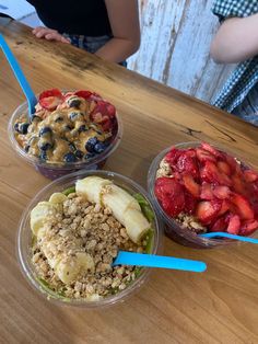 three plastic bowls filled with different types of food on top of a wooden table next to a woman