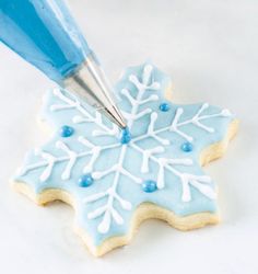 a cookie decorated like a snowflake with icing being piped into it