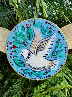 an ornament hanging from a christmas tree decorated with blue and gold designs, featuring a dove