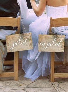 two people sitting on wooden chairs with signs in front of them that read pilot copilod