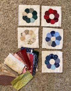 four square pieces of fabric sitting on top of a floor next to each other with different designs