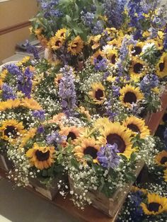 a bunch of sunflowers and other flowers are arranged in baskets on a table