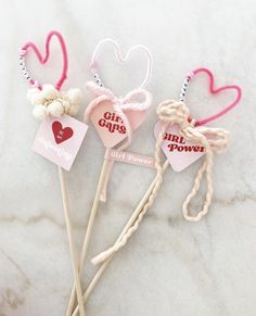 three heart shaped lollipops on top of a marble table with tags attached to them