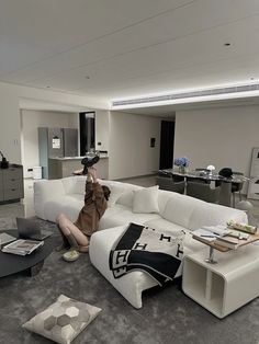 a woman sitting on top of a white couch in a living room next to a table