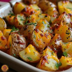 a white dish filled with potatoes covered in sauce