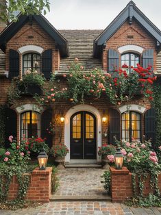 a brick house with lots of flowers growing on the front and side windows, along with potted plants