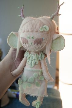 a small stuffed animal is being held up by someone's hand and wearing a dress