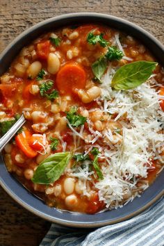 a bowl of soup with beans, carrots and parmesan cheese on top