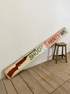 a wooden sign that says shoot 3 happy's in front of a stool